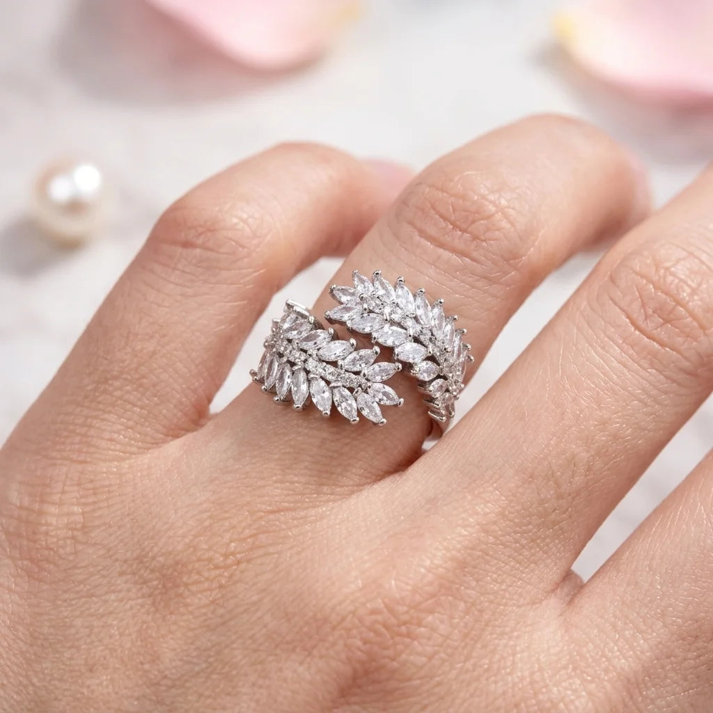 Silver leaf-shaped ring on a person's finger with a soft focus background