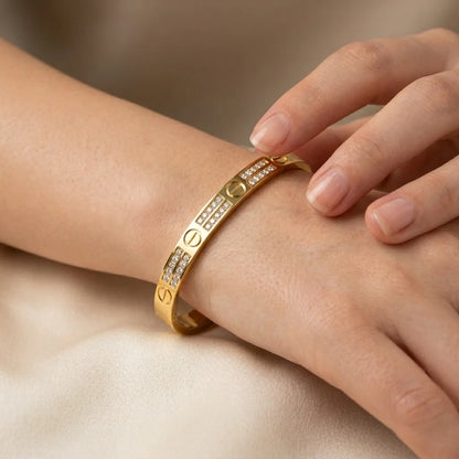 Gold bracelet with diamond accents on a wrist against a neutral background