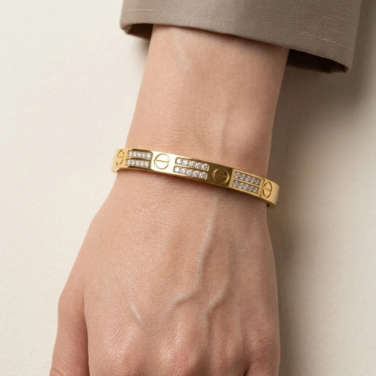 Gold bracelet with diamond accents on a wrist against a neutral background