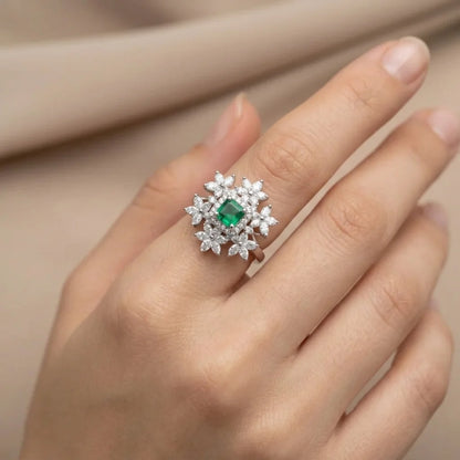 Ring with a green gemstone on a hand against a beige background