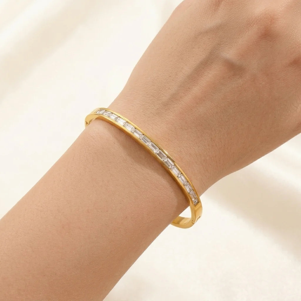 Gold bracelet with clear stones on a wrist against a light background