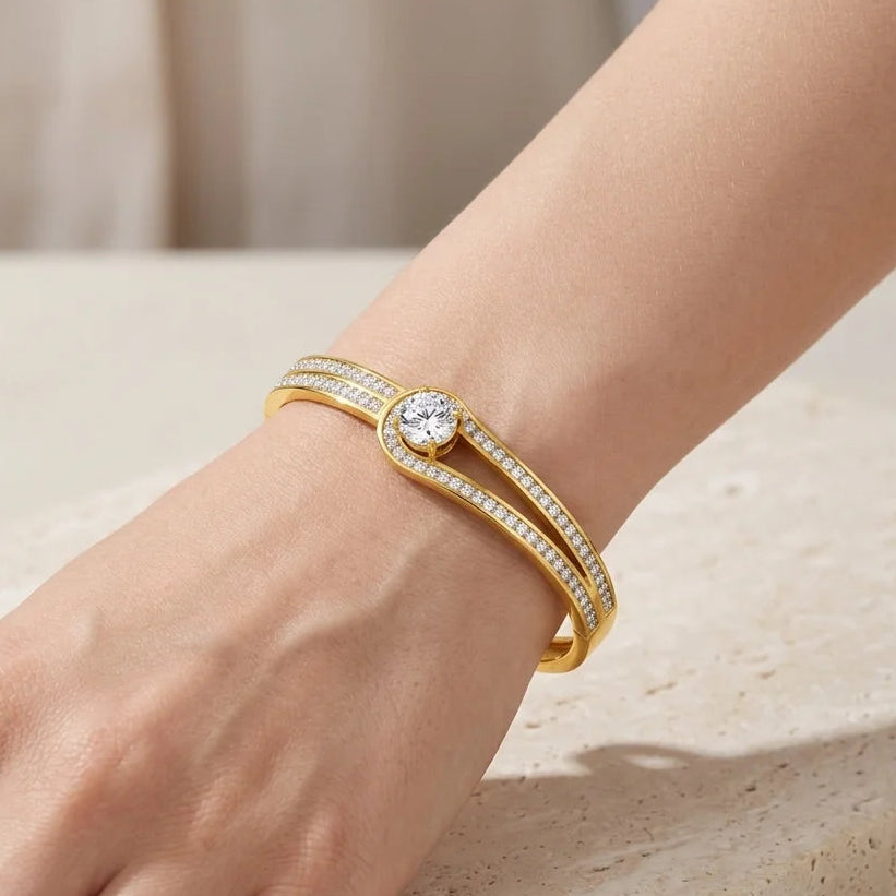 Gold bracelet with a diamond on a wrist against a neutral background