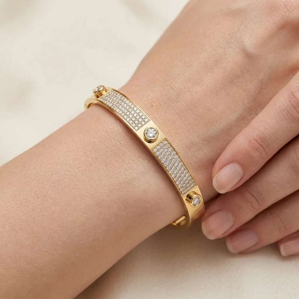 Gold bracelet with diamond accents on a wrist against a beige background