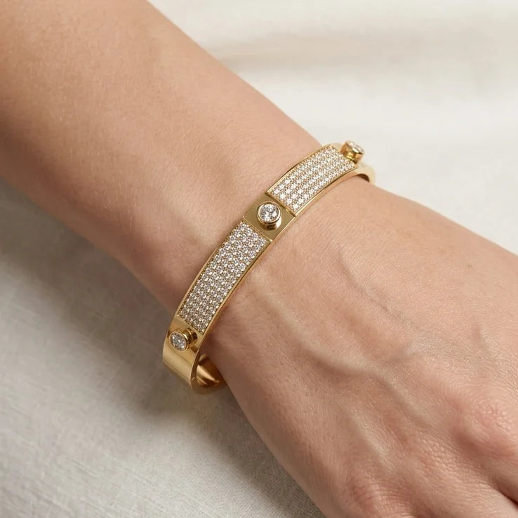 Gold bracelet with crystals on a hand against a neutral background