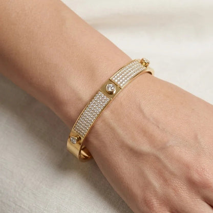 Gold bracelet with crystals on a hand against a neutral background