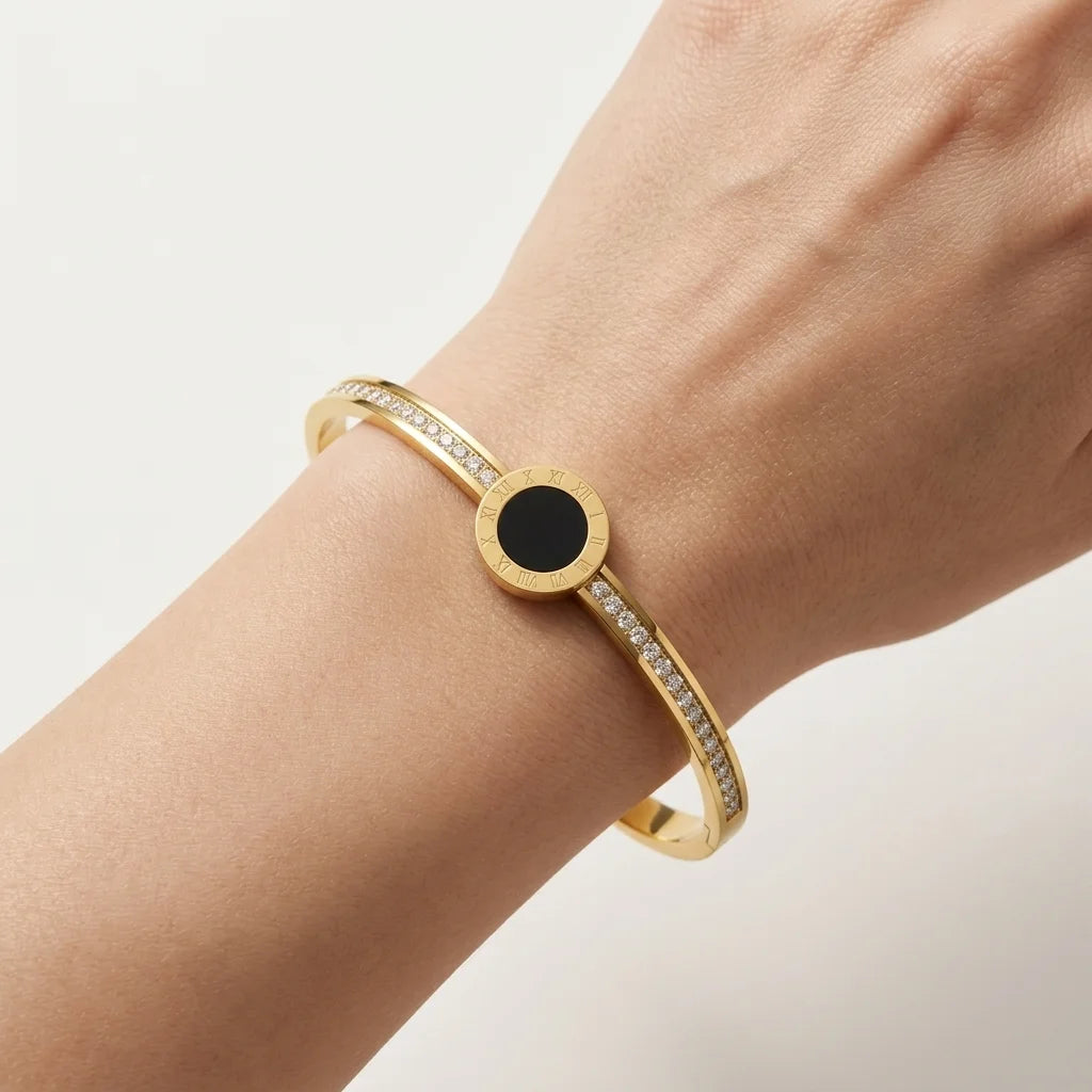 Gold bracelet with a black center stone on a wrist against a light background