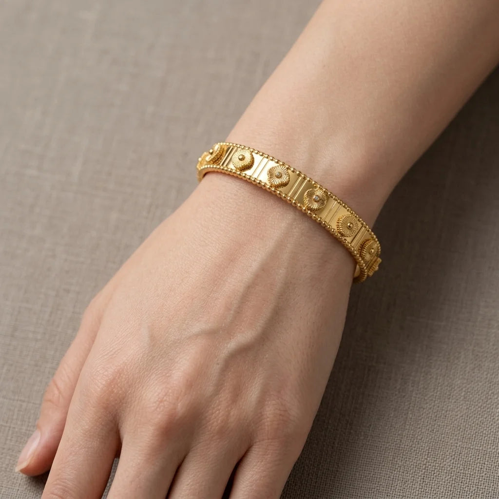 Gold bracelet on a wrist against a neutral background