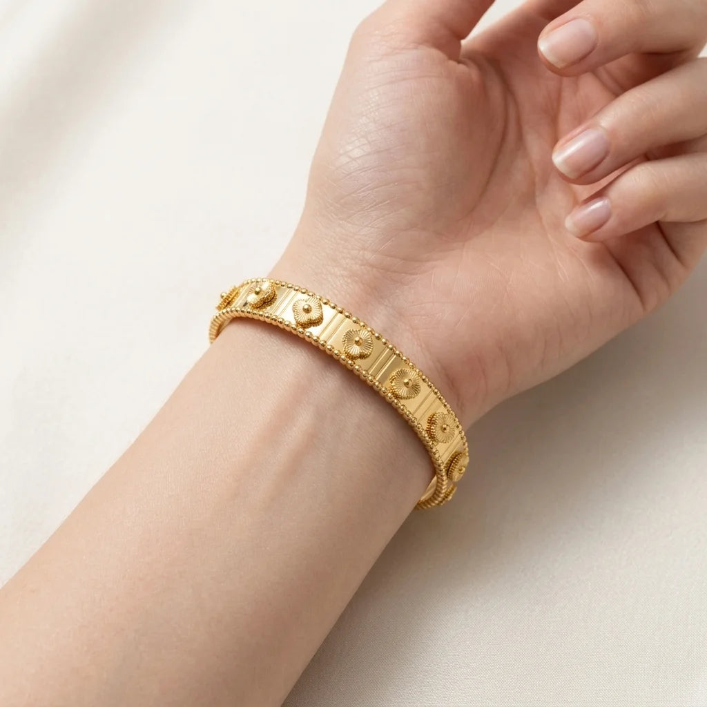 Gold bracelet on a wrist with a plain background