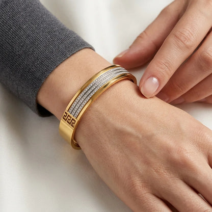 Gold bracelet on a wrist with a neutral background