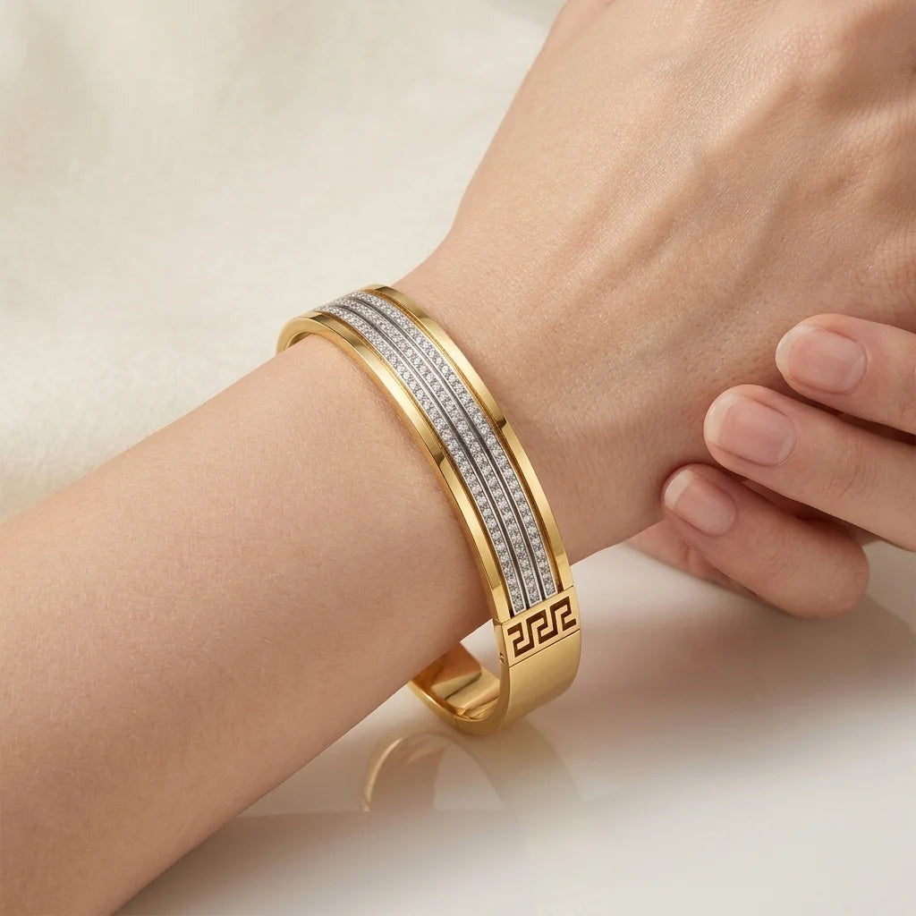 Gold bracelet with diamond accents on a wrist against a neutral background