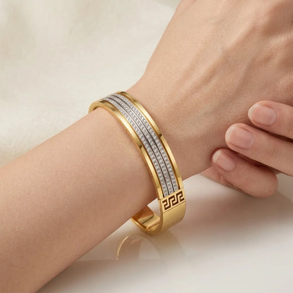Gold bracelet with diamond accents on a wrist against a neutral background