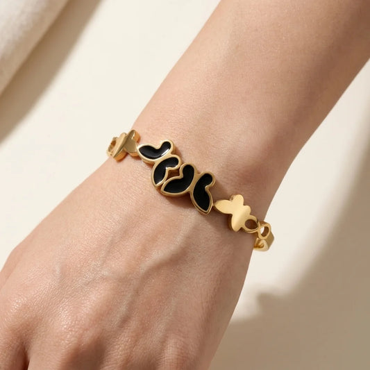 Gold and black butterfly bracelet on a wrist against a neutral background
