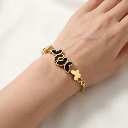 Gold bracelet with black accents on a wrist against a white background
