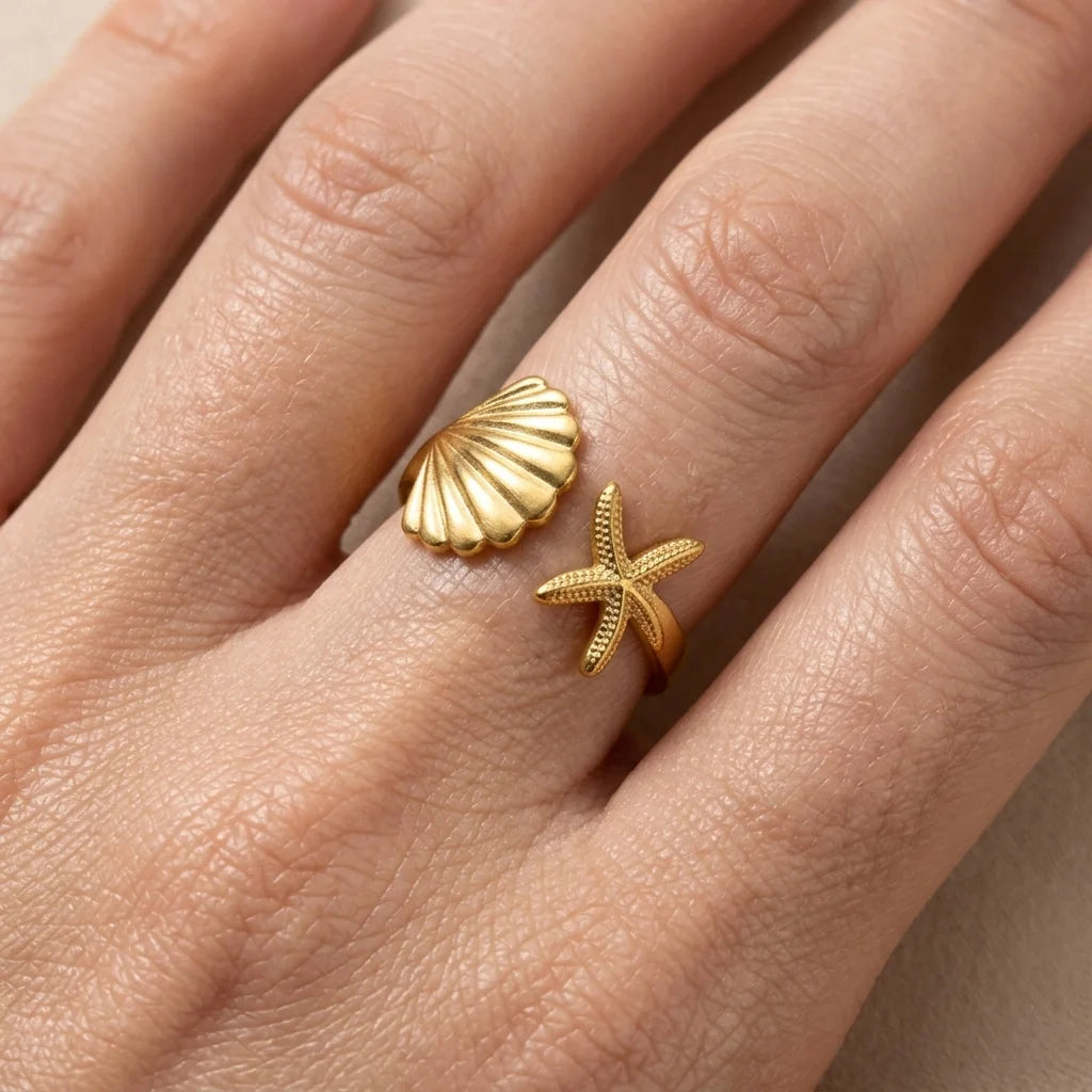 Gold shell and starfish rings on a person's finger