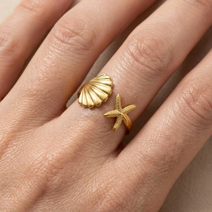Gold shell and starfish rings on a person's finger