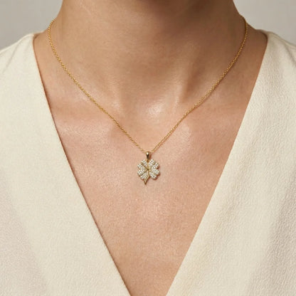 Gold necklace with a diamond pendant worn by a person against a neutral background