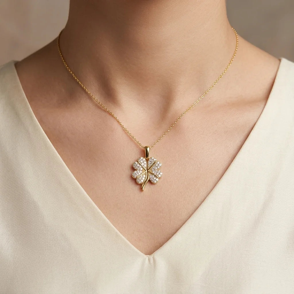 Gold necklace with a diamond pendant worn by a person in a cream top.