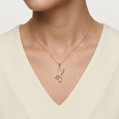 Gold necklace with a pendant worn by a person against a neutral background