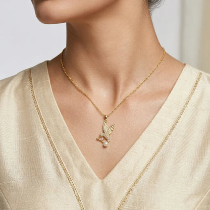 Gold necklace with a pendant worn by a person in a light-colored outfit.