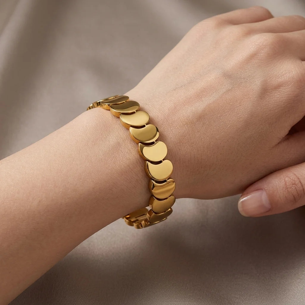 Gold bracelet on a wrist against a neutral background