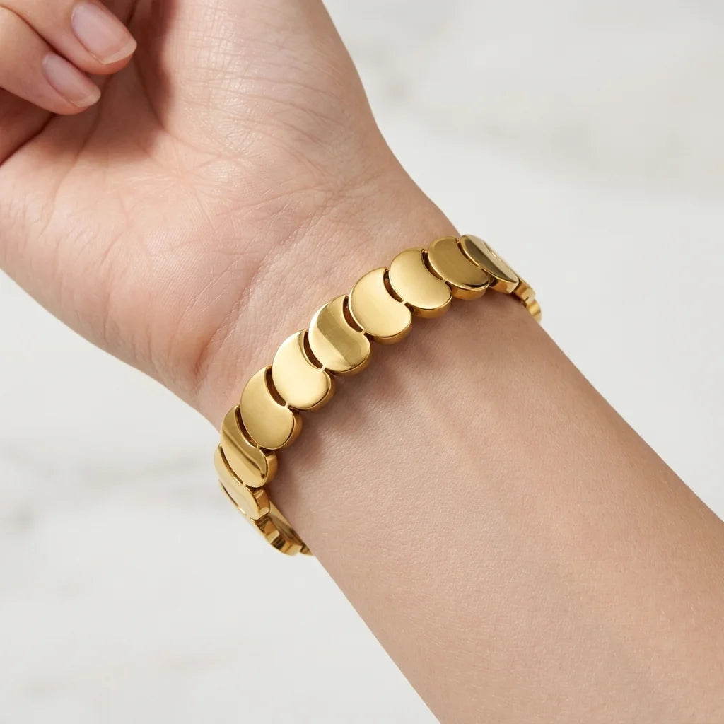 Gold bracelet on a person's wrist against a white background