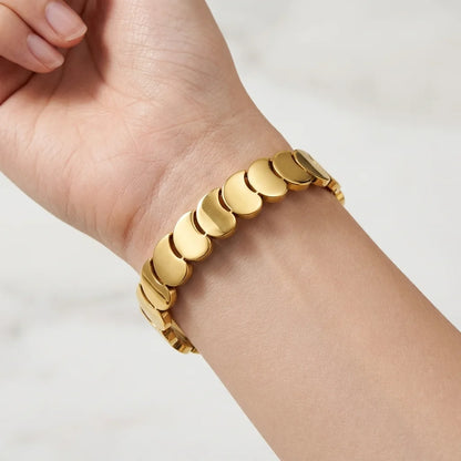 Gold bracelet on a person's wrist against a white background
