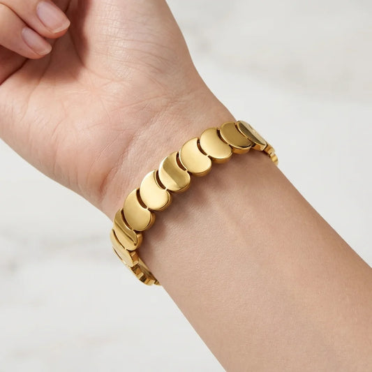 Gold bracelet on a person's wrist against a white background
