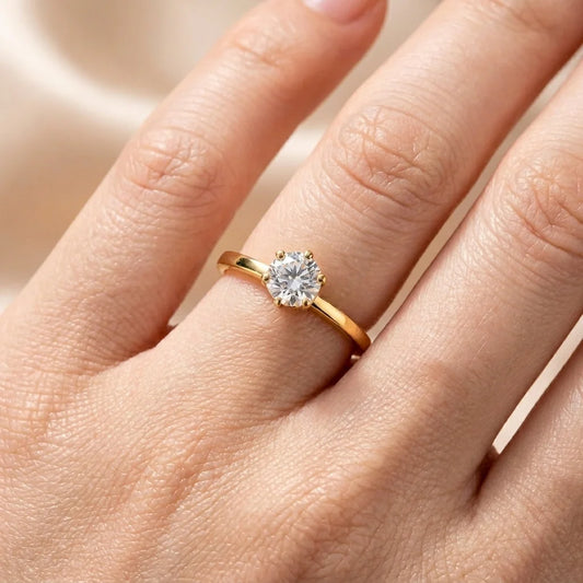 Gold ring with a diamond on a hand against a neutral background