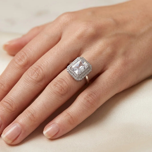 Silver ring with a large diamond on a hand against a neutral background