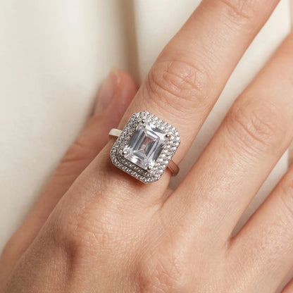 Silver ring with a large diamond on a hand against a neutral background