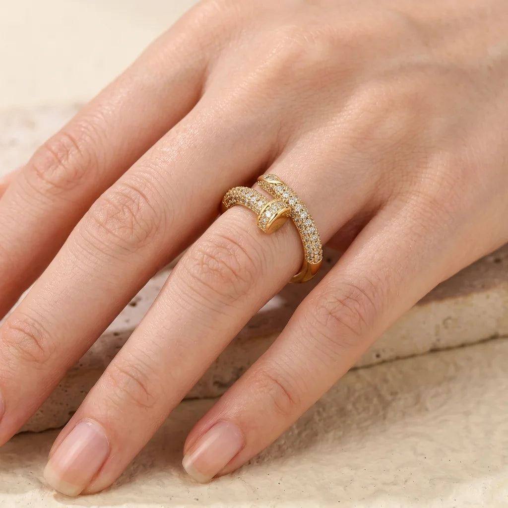 Gold ring with diamonds on a finger against a neutral background