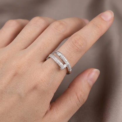 Hand wearing a silver ring with multiple diamonds on a neutral background