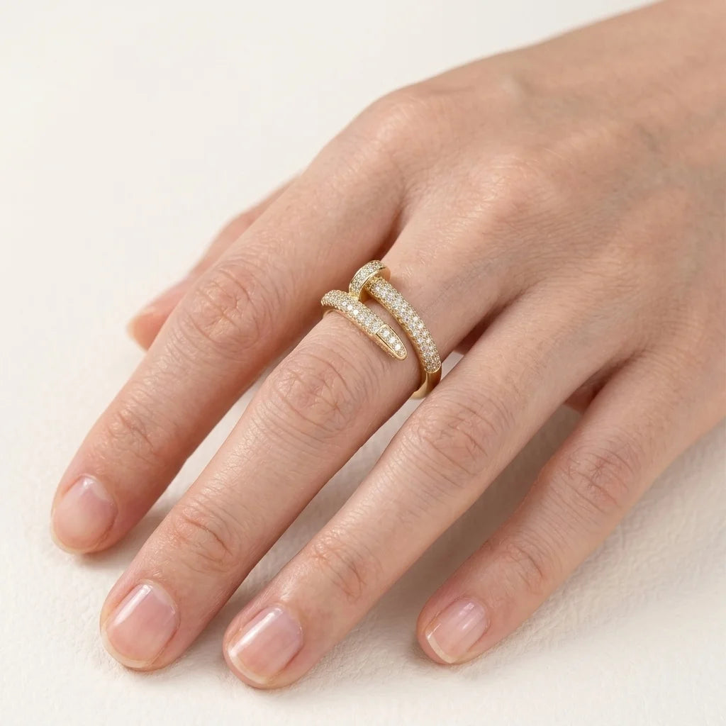 Hand wearing a gold ring with diamonds on a light background