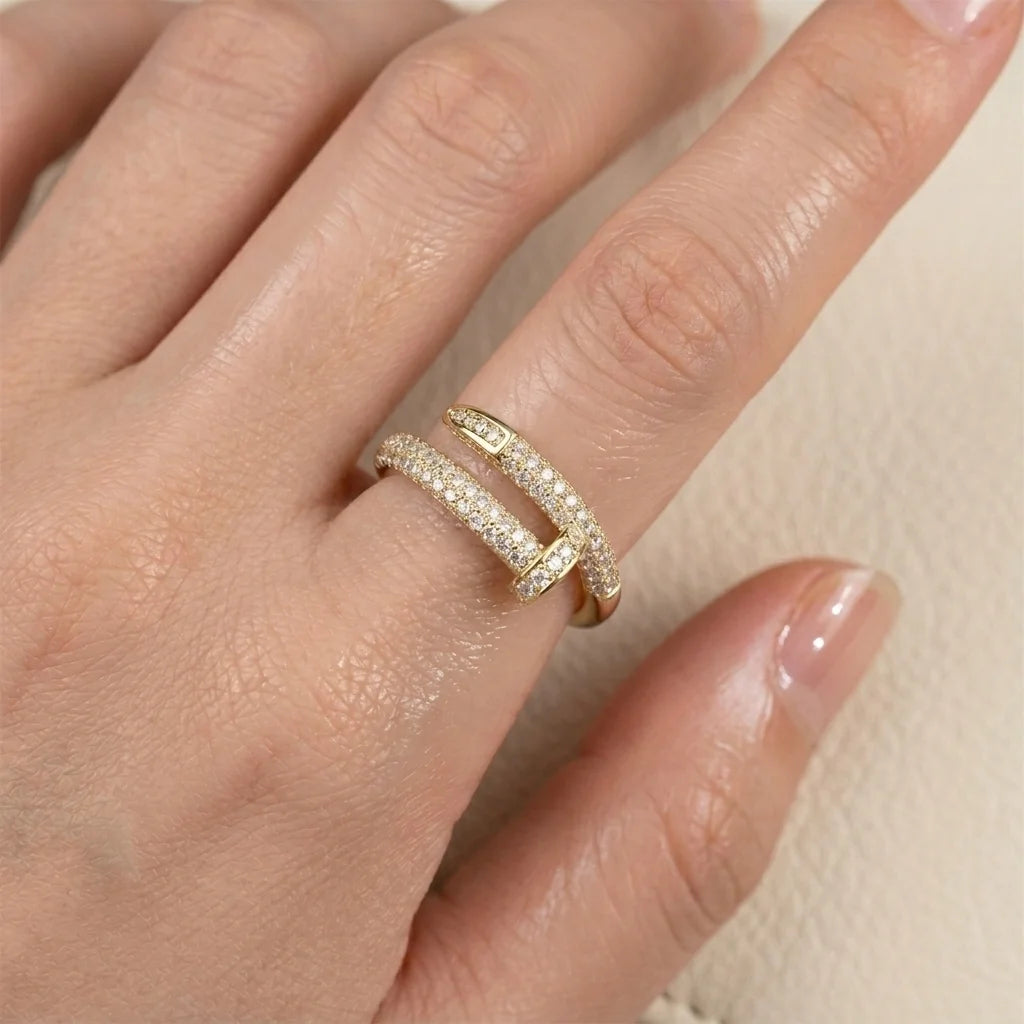 Gold ring with diamonds on a hand against a neutral background