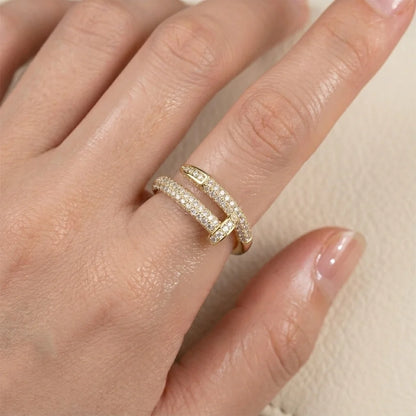 Gold ring with diamonds on a hand against a neutral background