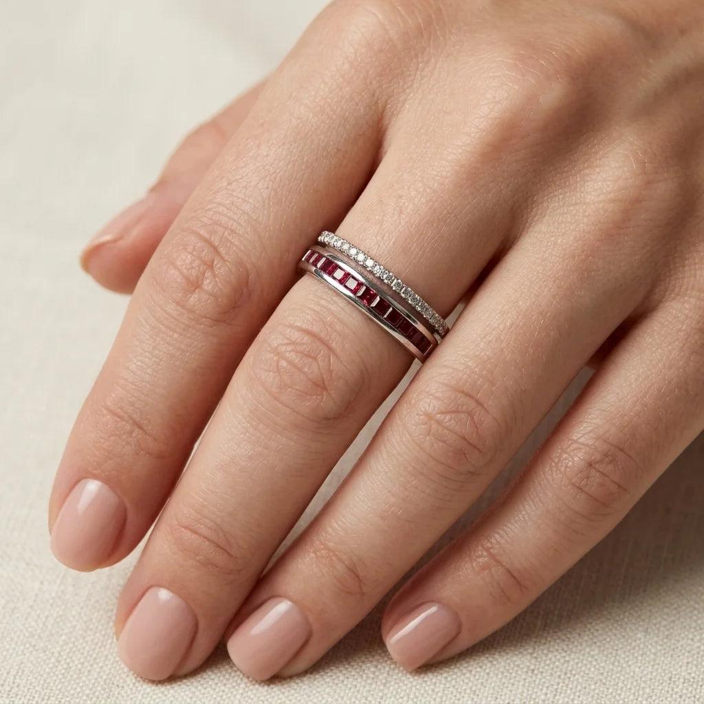 Close-up of a hand wearing two rings on a neutral background