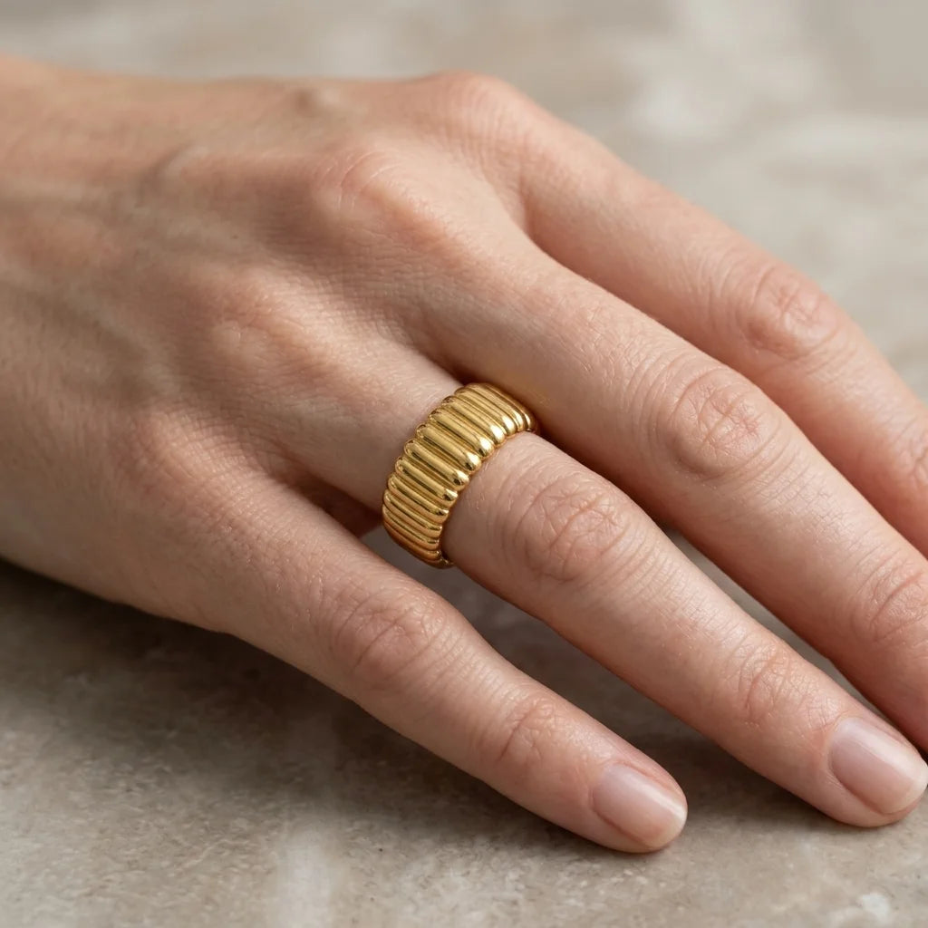 Gold ring on a person's finger against a neutral background