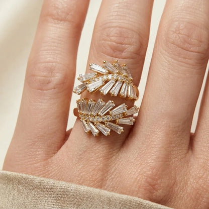 Gold and diamond ring on a finger against a neutral background