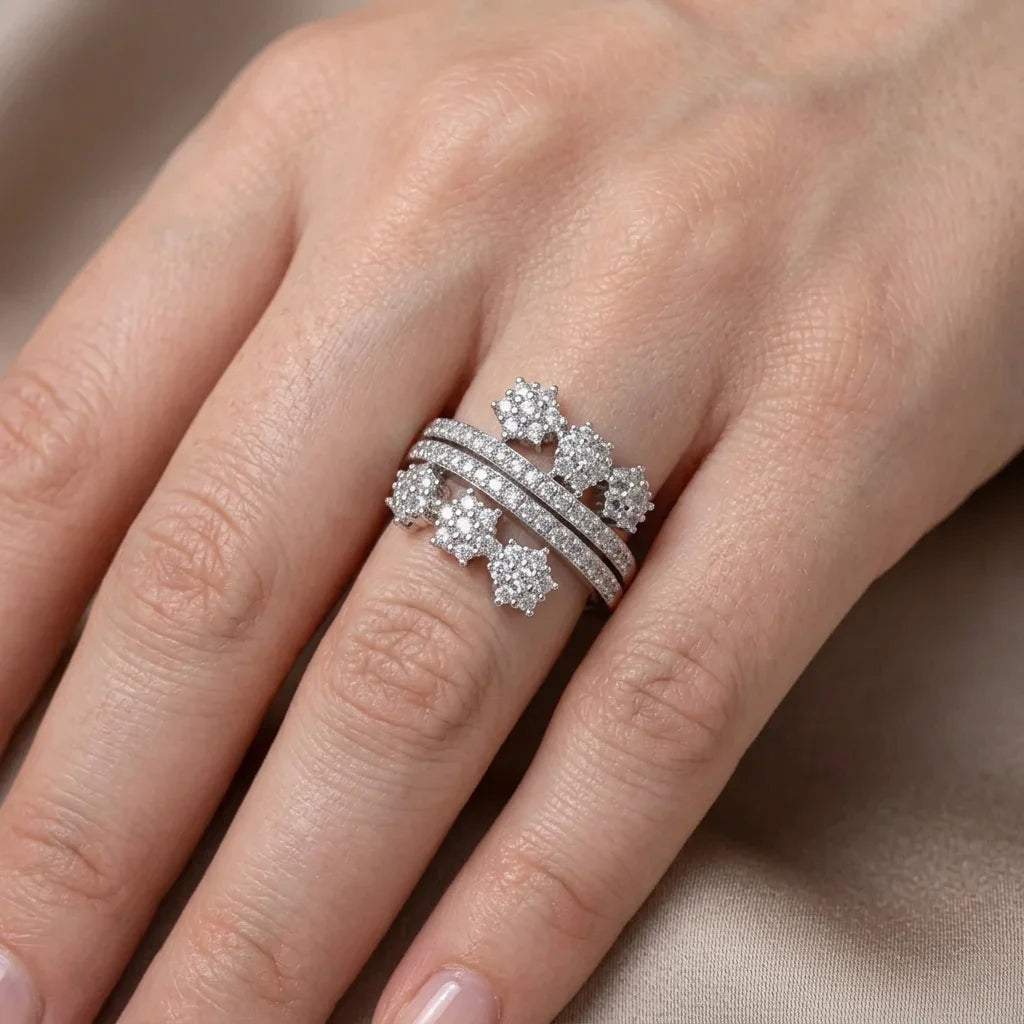 Silver ring with floral design on a finger against a neutral background