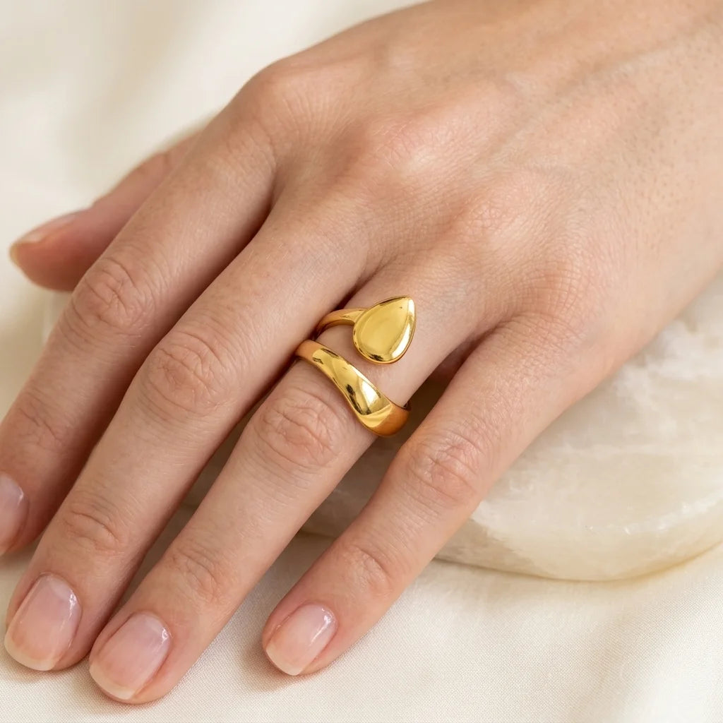 Gold ring on a finger against a neutral background