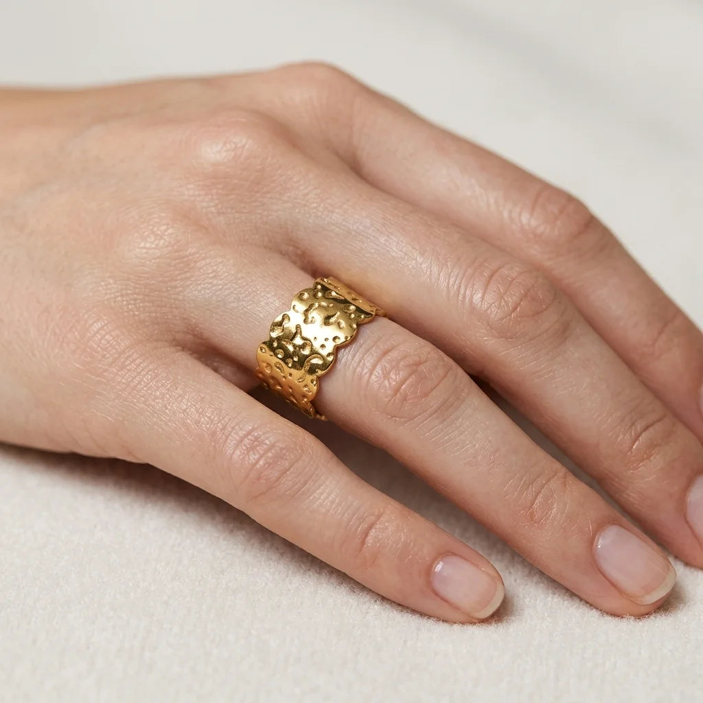 Gold ring on a person's finger against a neutral background