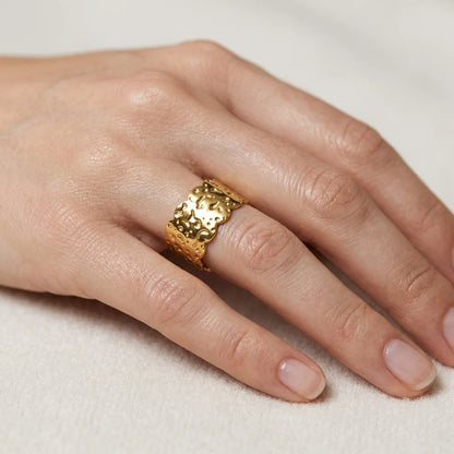 Gold ring on a person's finger against a neutral background