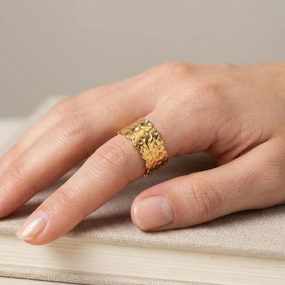 Gold ring on a finger with a neutral background