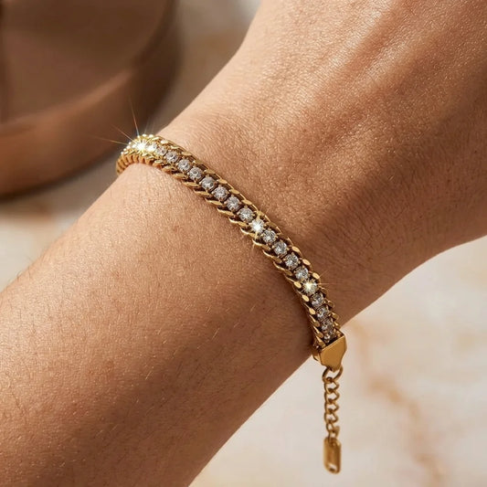 Gold bracelet with diamonds on a wrist against a neutral background
