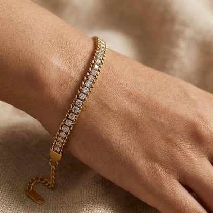 Gold bracelet with diamonds on a wrist against a neutral background
