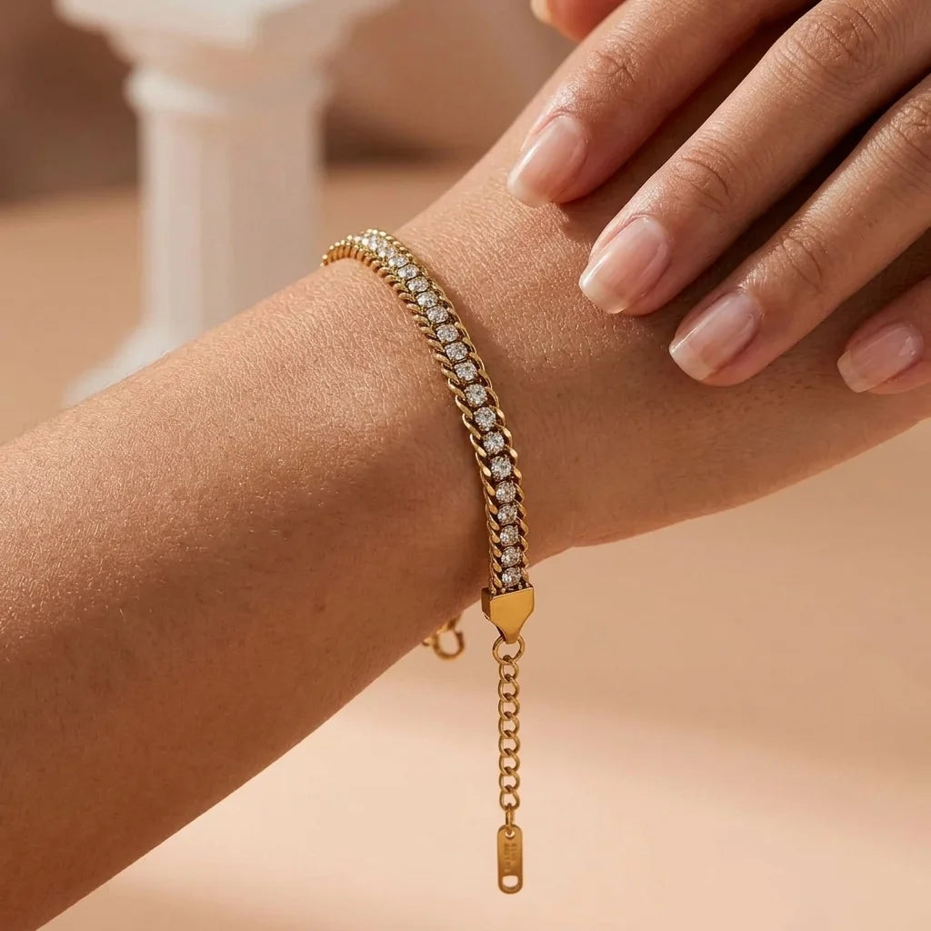 Gold bracelet with clear stones on a wrist against a neutral background