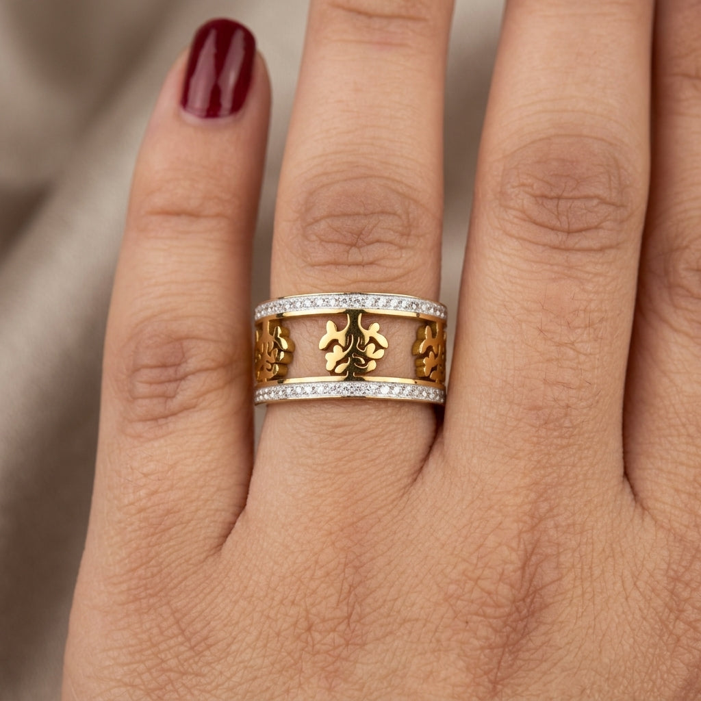 Gold ring with floral design on a finger against a neutral background