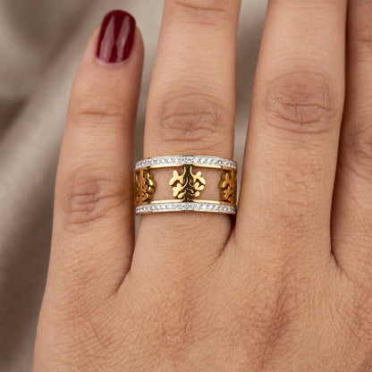 Gold ring with floral design on a finger against a neutral background