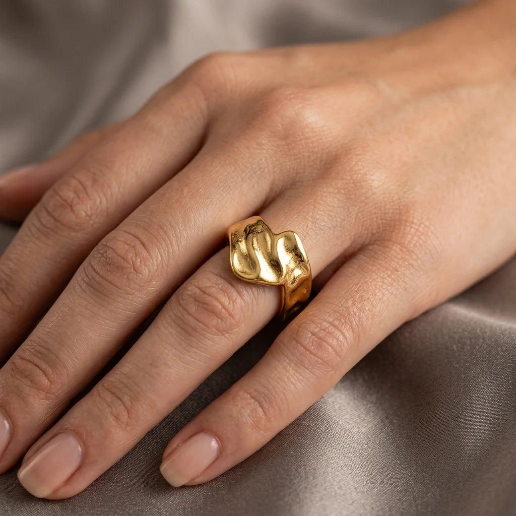 Gold ring on a person's finger against a neutral background