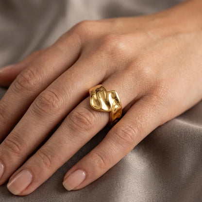 Gold ring on a person's finger against a neutral background